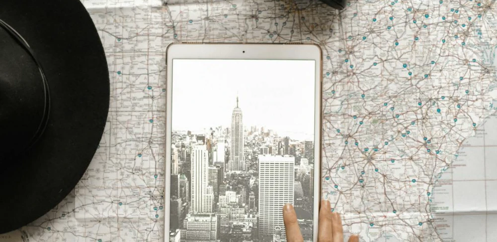 Travel designer planejando roteiro personalizado no iPad sobre o mapa mundial.